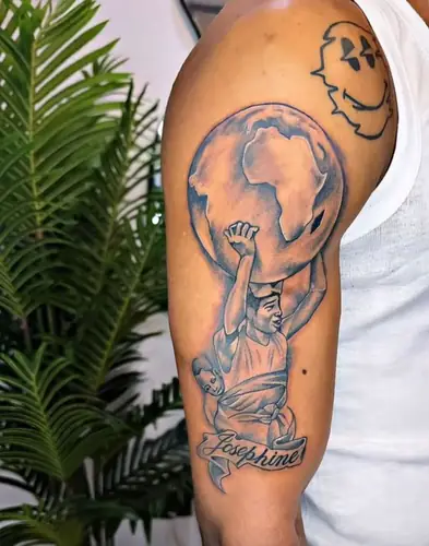 Man carrying globe with Africa, child on back, Josephine banner — tattoo