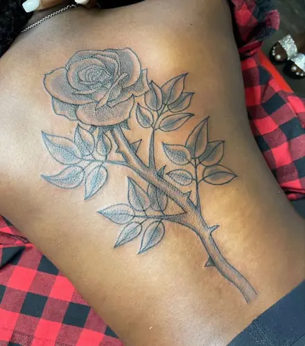 Rose with thorny stem — side torso tattoo