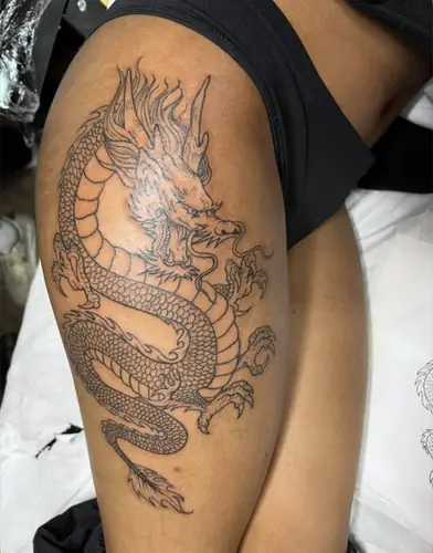 Dragon coiled — thigh tattoo